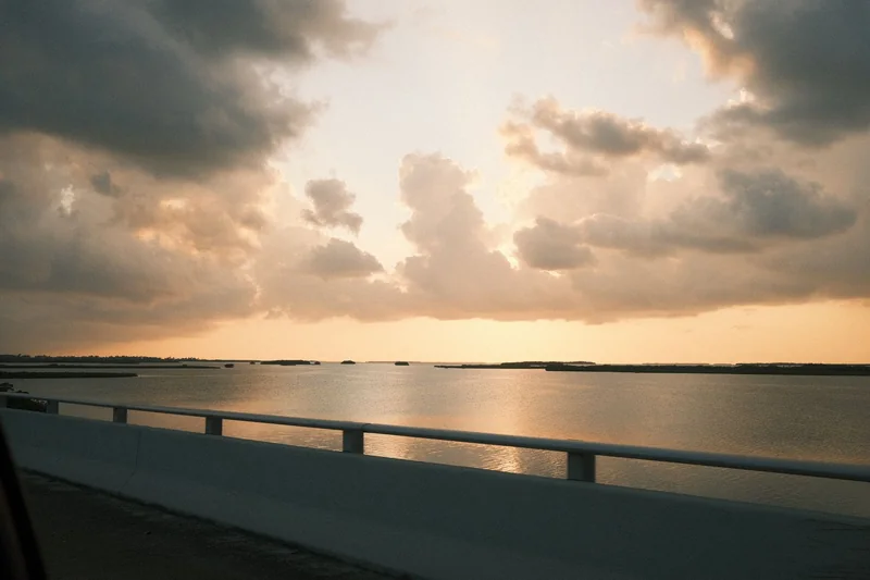 Golden-hour clouds over calm water and mangrove islands, seen from a bridge in the Florida Keys