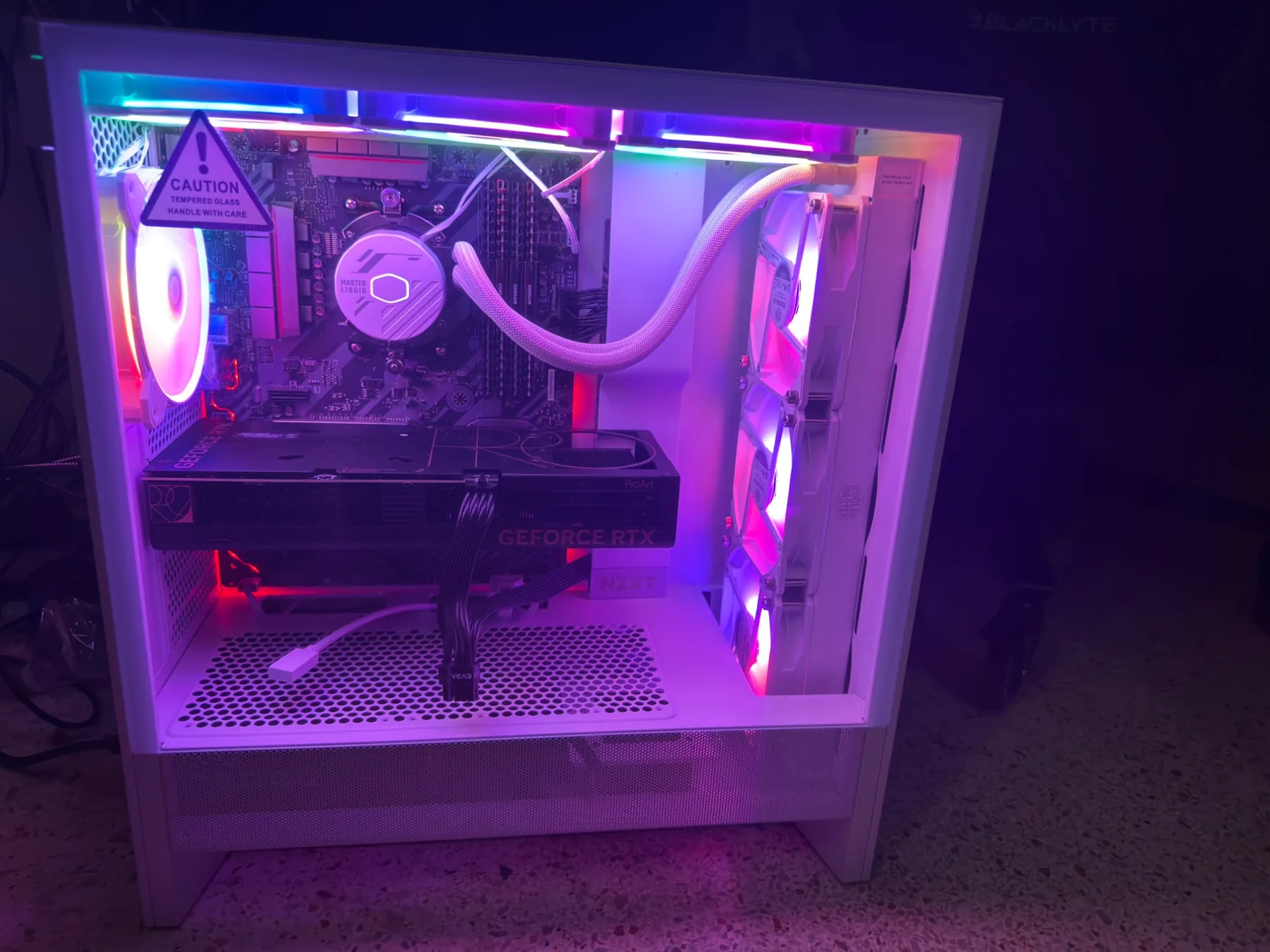 The desktop PC lit in violet, showing the ASUS ProArt RTX graphics card and Cooler Master liquid cooler