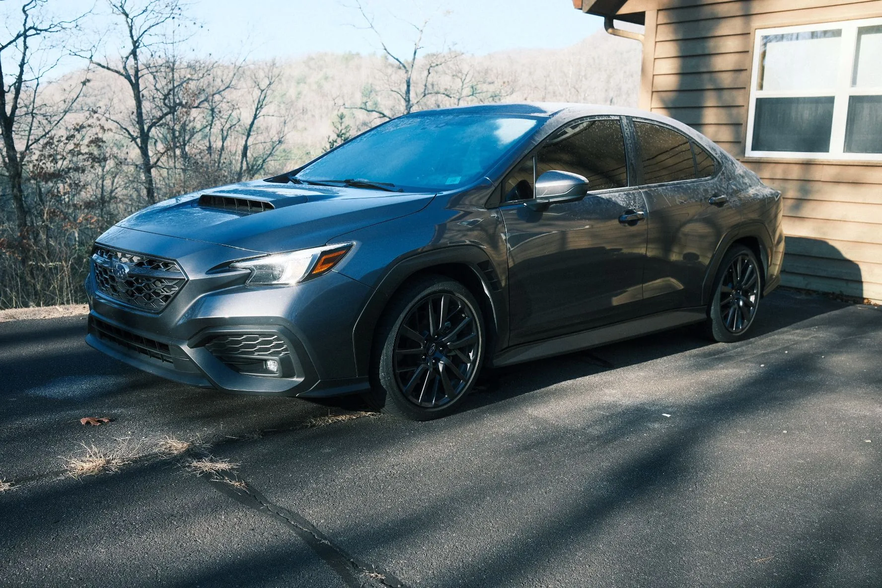 Gray 2022 Subaru WRX parked on a driveway on a frosty morning with bare trees and mountains behind it